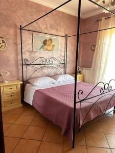 a bedroom with a black canopy bed with pink sheets at A casa di Ale in Frascati