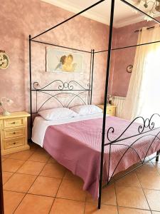 a bedroom with a black canopy bed with pink sheets at A casa di Ale in Frascati