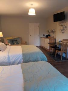 a bedroom with two beds and a table and a kitchen at Mulberry Lodge in Blarney