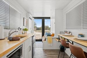 a kitchen with white cabinets and a table with chairs at New Oak Grove-Container Retreat in Fredericksburg