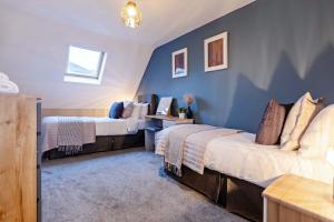Duas camas num quarto com paredes azuis em Quaint 3 bedroom Cottage with Private Parking by Eagle Owl Property em Worthing