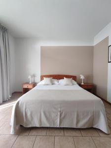 una camera da letto con un grande letto bianco con due tavoli di Agriturismo La Vigna a Colà