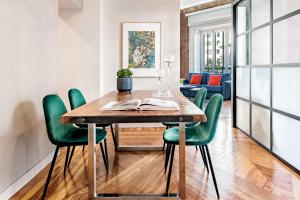 a dining room with a wooden table and green chairs at Premium Belgravia Harrods Apartment in London