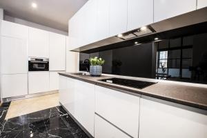 a kitchen with white cabinets and a black counter top at Premium Belgravia Harrods Apartment in London