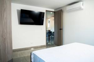 a bedroom with a bed and a flat screen tv on the wall at Apartamento frente al CC Viva Envigado in Envigado