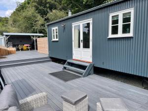 a green house with a deck and a patio at The Grove Glamping in Cromer