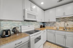 a kitchen with white cabinets and white appliances at Lovely Resort Low Floor Condo! Just Steps to the Beach & Restaurants! by Dolce Vita Getaways PCB in Panama City Beach