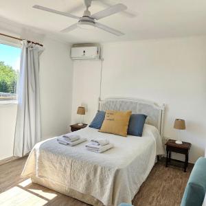 um quarto com uma cama com almofadas azuis e uma ventoinha de tecto em Jacarandá, amplio departamento con terraza em Chascomús