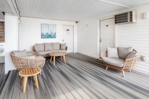 a porch with two chairs and a couch and tables at The Atlantic Motel in Hampton