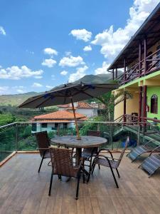 una mesa y sillas con una sombrilla en la cubierta en Pousada Inconfidência Mineira, en Ouro Preto