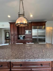 a kitchen with a granite counter top and a chandelier at 5 Plus Bedroom Over Sized Colonial in Very Private Setting in Pound Ridge