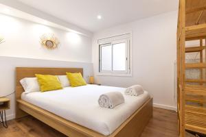 ein Schlafzimmer mit einem großen weißen Bett mit gelben Kissen in der Unterkunft Picasso Suites Cornellá 2.2 in Cornellà de Llobregat