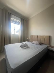 Bett mit Hut und Fenster in der Unterkunft Apartamento Completo - Algarve 203 e 204 in Patos de Minas