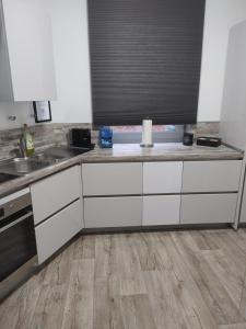 a kitchen with white cabinets and a wooden floor at Haus am Waldrand in Bad Hersfeld