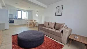 uma sala de estar com um sofá e um banco em X rent apartment em Prim Decembrie