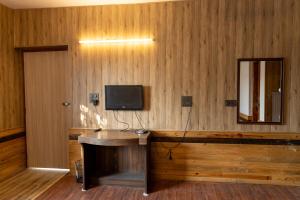 a room with a desk with a television and a mirror at Bali guest house in Srinagar