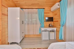 a room with a bed and a desk and a tv at Simge Pension in Cıralı