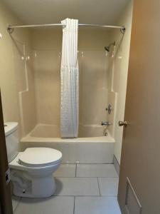 a bathroom with a toilet and a tub and a shower at Scottish Inn & Suites - Eau Claire in Eau Claire