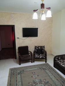 uma sala de estar com 2 cadeiras e uma televisão de ecrã plano em الشقة العائلية الحديثة em Amã