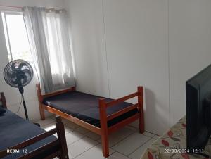 a room with a bed and a fan and a window at Hostel Canarios in Palhoça