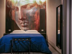 um quarto com uma pintura de um rosto na parede em Dea's Rooms em Noto