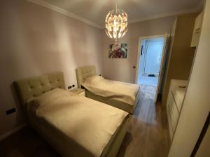 Habitación pequeña con 2 camas y lámpara de araña. en Apartament Tirana, en Tirana