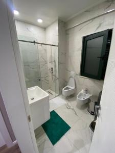 TV y baño con lavabo y aseo. en Apartament Tirana, en Tirana