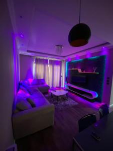sala de estar con iluminación púrpura y sofá en Apartament Tirana, en Tirana