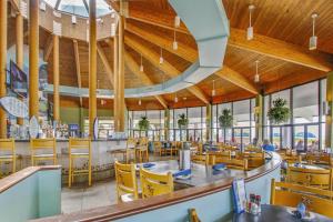 un restaurante con techos de madera, mesas y sillas amarillas en Edgewater Golf Villas #1506, en Panama City Beach