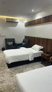 um quarto de hotel com duas camas e uma cadeira em درة الشرق للشقق المخدومة em Sīdī Ḩamzah