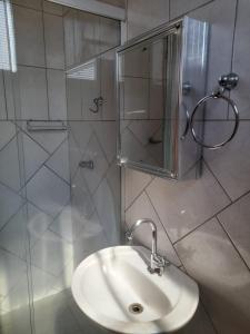a bathroom with a sink and a glass shower at Quarto para temporada in Ribeirão Preto