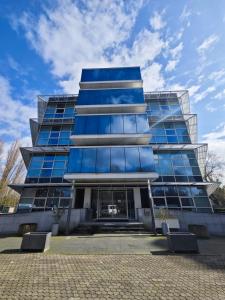 un grand bâtiment en verre avec un ciel bleu en arrière-plan dans l'établissement Diamond Capsule Hotel Amsterdam South, à Amstelveen