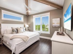 a bedroom with a white bed and two windows at Luxe Island Escape in Anna Maria
