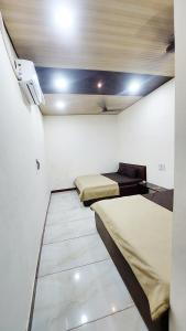 Habitación con 2 camas y TV en la pared. en HOTEL PRAKASH PALACE, en Ujjain