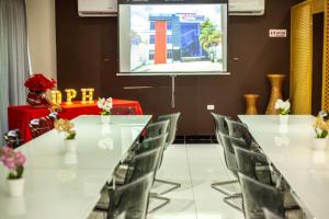 uma sala de conferências com mesas e cadeiras brancas e um ecrã de projecção em Dpravia Hotel SRL em Baní