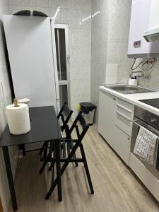 uma cozinha com uma mesa preta e duas cadeiras em A 5 min del aeropuerto + IFEMA em Madri