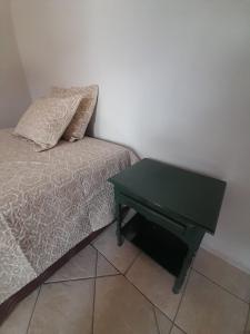 a bed with a green table next to a bed with a pillow at Quarto para temporada in Ribeirão Preto