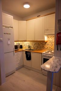 La cuisine est équipée de placards blancs et d'un réfrigérateur blanc. dans l'établissement Cozy Apartment by the Sea, à Kemi