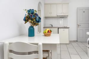 a white kitchen with a vase of flowers and fruit on a counter at Depis studios & apartments in Naxos Chora