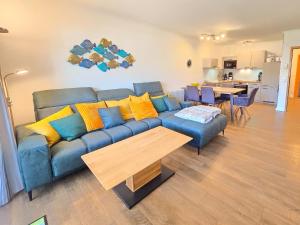 ein Wohnzimmer mit einem blauen Sofa und einem Tisch in der Unterkunft Dünenpark Binz - Komfortplus Ferienwohnung mit 2 Schlafzimmern und Terrasse im Erdgeschoss 166 in Binz