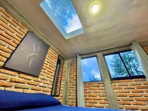 1 dormitorio con pared de ladrillo y ventanas en Cabaña Hermosa Bosque Privado 19 en Mineral del Monte