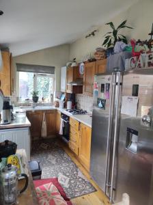 a kitchen with wooden cabinets and a stainless steel refrigerator at Cosy London single room (near Wimbledon) in London