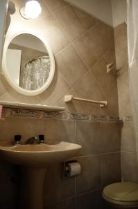 y baño con lavabo, espejo y aseo. en Hostería Robert en Villa Gesell