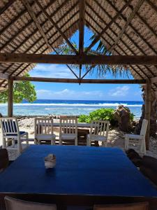 Tifaifai Et Café Huahine في فار: طاولة وكراسي على شاطئ مع المحيط