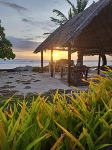 une cabane sur la plage avec le coucher du soleil en arrière-plan dans l'établissement Tifaifai Et Café Huahine, à Fare