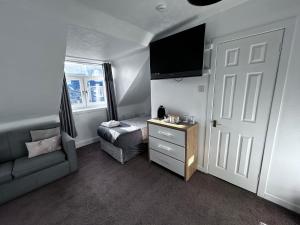 Habitación pequeña con cama, silla y TV. en DunMoore Guesthouse, en Oban