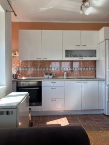 uma cozinha com armários brancos e uma parede de tijolos em Apartman PRESSTIGE em Smederevska Palanka