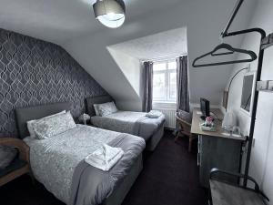 una camera d'albergo con due letti e una televisione di DunMoore Guesthouse a Oban Altre 37 foto