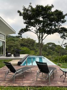 a swimming pool with two chairs and a table at Villa Luz in Villavicencio