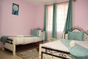 1 dormitorio con 2 camas y ventana en Laucinas homes en Nakuru